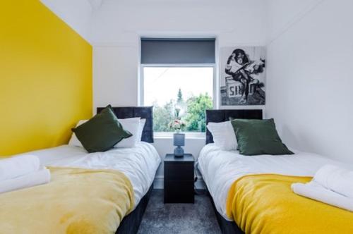 duas camas num quarto com amarelo e branco em SPECIAL RATE FOR BOOKINGS MORE THAN 7 NIGHTS, WARM SPACIOUS CONTRACTOR HOUSE NEAR LIVERPOOL CITY CENTRE SLEEPS 8 kitchen & dining room, washing machine em Liverpool