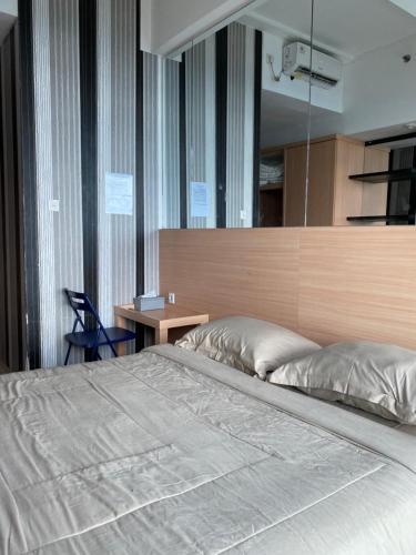 a bedroom with a large bed and a desk at RoomQu at Apartment Tree Park in Kebonnanas