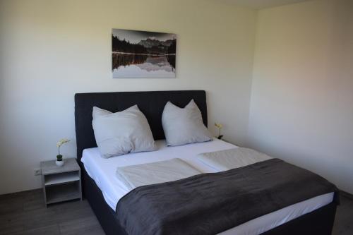 una camera da letto con un letto grande con lenzuola e cuscini bianchi di Rebekka‘s Apartment a Füssen