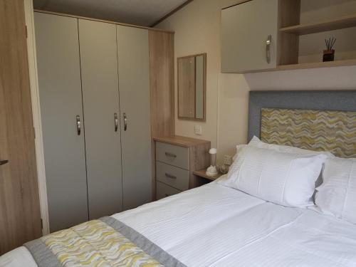 a bedroom with a bed with white sheets and cabinets at 2 Bedroom Lodge, Milford on Sea in Milford on Sea
