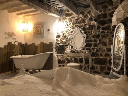 La salle de bains est pourvue d'une baignoire et d'un mur en pierre. dans l'établissement L'Olivray, à Callian