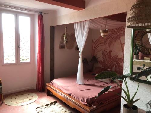 une chambre avec un lit à baldaquin et une fenêtre dans l'établissement L'Olivray, à Callian