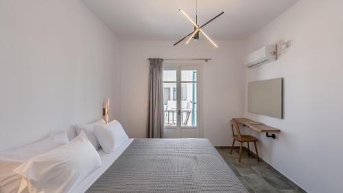 a bedroom with a bed with a ceiling fan and a desk at Michalis Studios in Pollonia