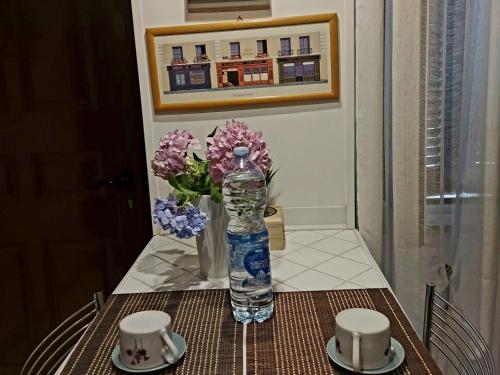 a bottle of water sitting on a table with a vase of flowers at Delizioso appartamento Frosinone centro storico in Frosinone
