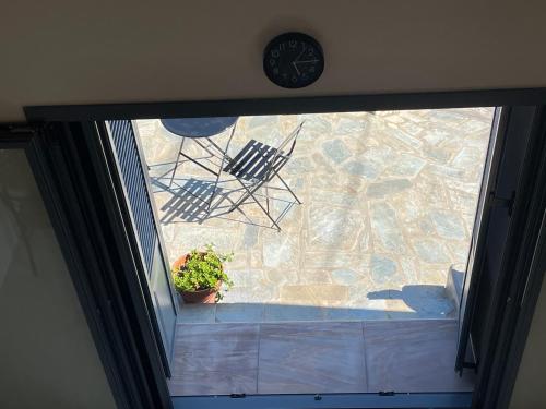 a window with a clock and two chairs and a plant at The Stone House in Votsi