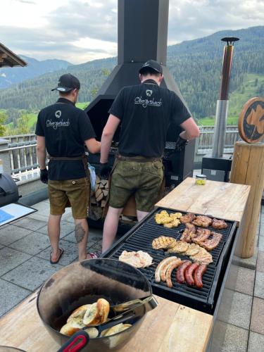 two men standing in front of a grill with food at Obergersbach in Floitensberg