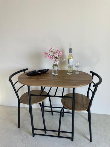 a wooden table with two chairs and a bottle of wine at The Stone House in Votsi