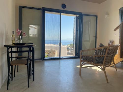 a living room with a table and chairs and a view of the ocean at The Stone House in Votsi