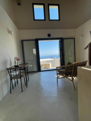 a living room with a table and chairs and a view of the beach at The Stone House in Votsi
