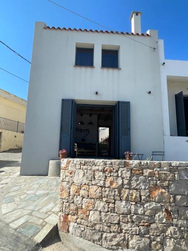 a white building with a blue door and a stone wall at The Stone House in Votsi