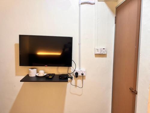 a flat screen tv sitting on a wall next to a door at Hotel Citra in Brinchang