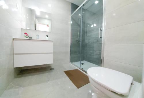 een witte badkamer met een toilet en een douche bij Estudios Center in Corralejo