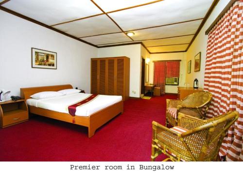 a hotel room with a bed and a chair at Nazimgarh Garden Resort in Sylhet