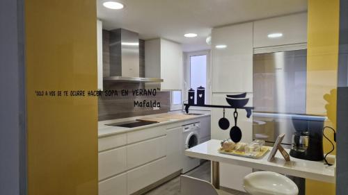 a kitchen with white cabinets and a yellow wall at Soleado a un paseo de la Catedral in Santiago de Compostela