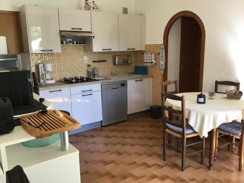 a kitchen with white cabinets and a table with chairs at Le petit gîte in Saint-Étienne-le-Laus