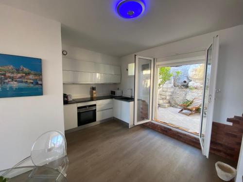 une cuisine avec une porte coulissante en verre menant à une terrasse. dans l'établissement Au cœur du Parc National du Massif des Calanques, la Flibuste des Goudes, Maison 2 chambres, climatisée, jardins, solarium, proche plage, large vue mer, à Marseille
