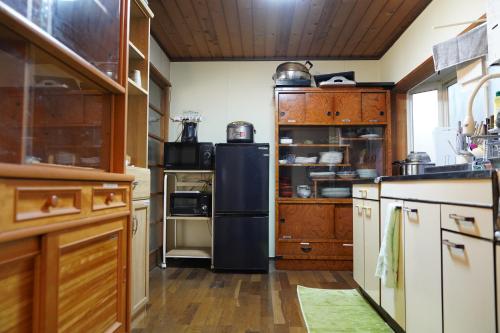 a kitchen with a black refrigerator and wooden cabinets at MAYUDAMAHOUSE in Higashiagatsuma