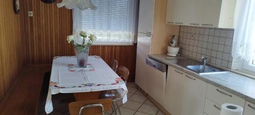 a kitchen with a table with a vase of flowers on it at 7 Flower Street Apartment in Šempeter pri Gorici