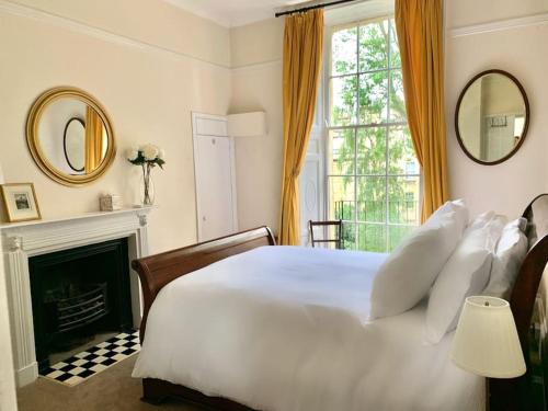 a bedroom with a large white bed and a fireplace at Beautiful Regency Crescent Apartment in Idyllic Location in Bath