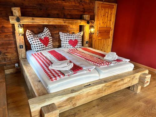 a wooden bed with red and white pillows on it at Ferienhaus Hexe mit Whirlpool, Sauna, Garten in Großschönau