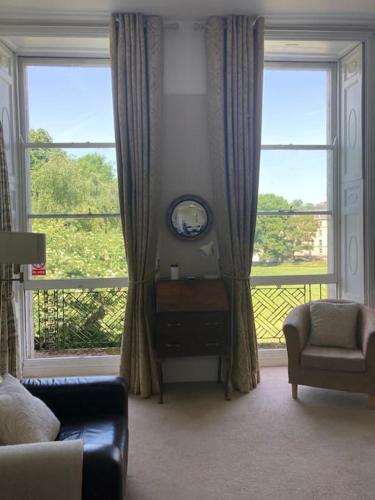 a living room with a large window and a clock at Beautiful Regency Crescent Apartment in Idyllic Location in Bath