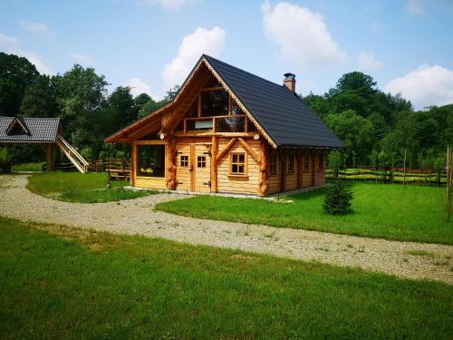 a log cabin with a black roof at Osada Strusie Jajo w Bieszczadach in Ustrzyki Dolne