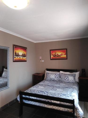 a bedroom with a bed and two pictures on the wall at Valley View Guest House in Mogwase