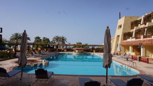 a large swimming pool with chairs and umbrellas at Tobya Village Hotel in Taba