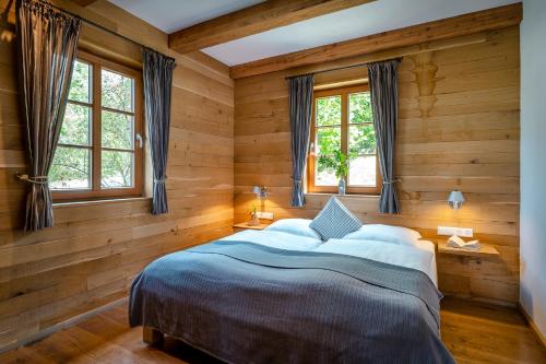 a bedroom with a bed with wooden walls and windows at Bergdorf LiebesGrün in Schmallenberg