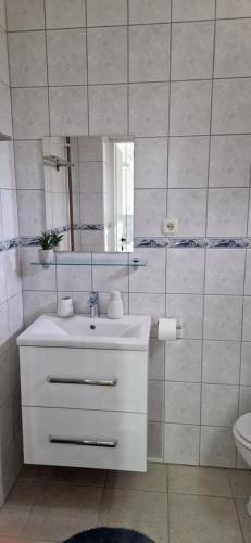 a white bathroom with a sink and a mirror at Sobe Majetic in Bizovac