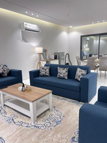 جناح فندقي في فله خاصة في أبها: غرفة معيشة مع أرائك زرقاء وطاولة قهوة