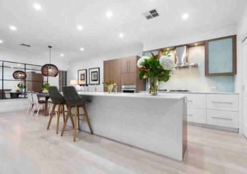 a kitchen with white cabinets and a counter with chairs at Executive living in City fringe location in Glenunga