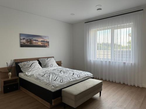 ein weißes Schlafzimmer mit einem Bett und einem Fenster in der Unterkunft Villa BEBRŲ NAMAI with Hot Tub in Ginduliai