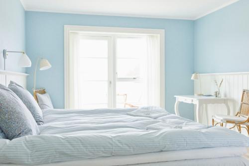 a white bed in a blue room with a window at Hjorths Badehotel in Kandestederne