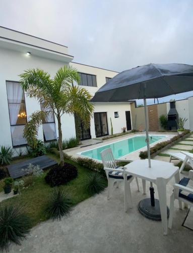 摩基達斯克魯易斯市的住宿－Casa Paradise Mogi，一个带桌子和遮阳伞的庭院和一个游泳池
