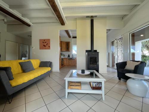 - un salon avec un canapé jaune et une cheminée dans l'établissement Le grand chinette, à Andoins
