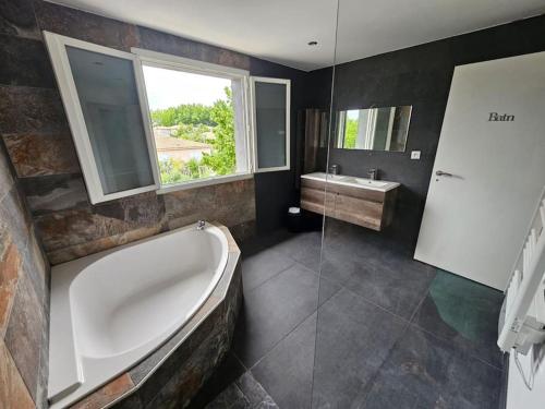 a large bathroom with a tub and a sink at Villa 4 chambres avec piscine. in Nîmes