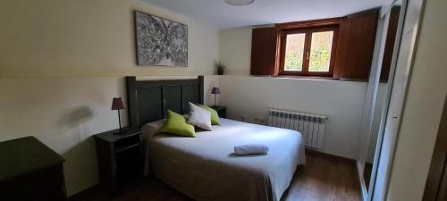 a bedroom with a white bed with green pillows and a window at MARGASOL in Pedrezuela