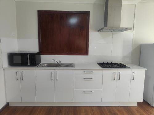 a white kitchen with a sink and a microwave at The Cozy little House in Armadale