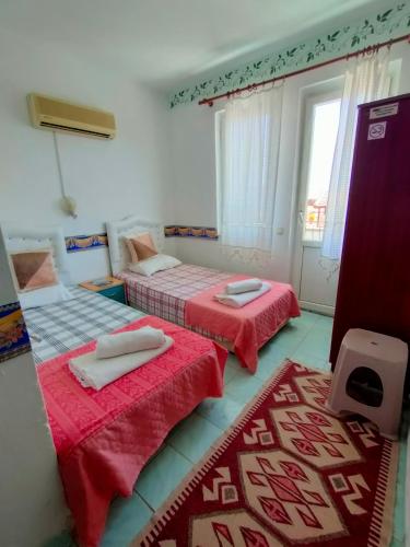 Habitación con 2 camas con sábanas rojas y ventana en ATHERİNA BUTİK OTEL, en Kas