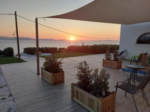 um pátio com uma mesa e cadeiras e o pôr-do-sol em Dionysus House and Ariadne Apartment em Stelida