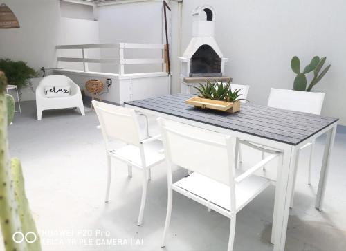 a dining room table with white chairs and a fireplace at Mare & Vento in Torre Lapillo