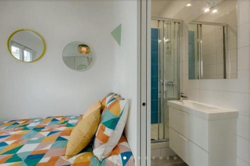 uma casa de banho com uma cama, um lavatório e um espelho. em Charmant 2 pièces calme et cosy em Paris
