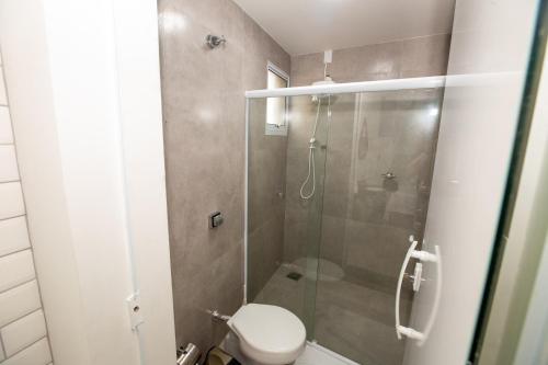 a bathroom with a toilet and a glass shower at Jahu Center Plaza Flats in Jaú