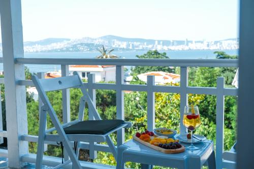 a plate of fruit and a glass of wine on a balcony at Kensington Prince's Island Historical Mansion in Adalar