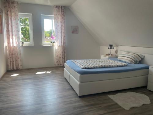 a white bedroom with a bed and a window at Lenis Kotte in Papenburg