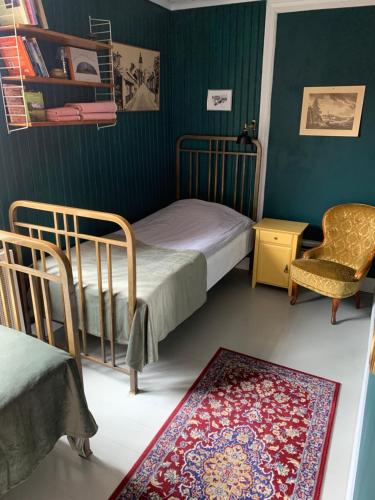 a bedroom with two beds and a chair and a rug at Pensionat Gyllenhjelmsgatan in Strängnäs