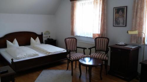 a bedroom with a bed and two chairs and a table at Landhotel St. Florian in Sankt Florian am Inn