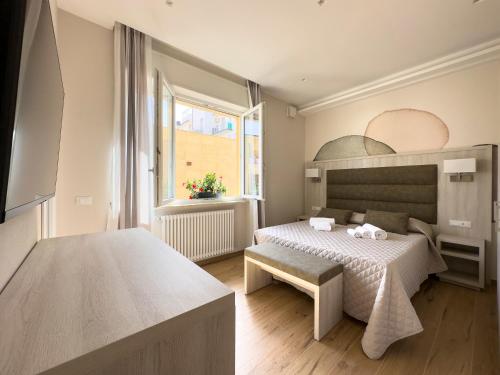 Versilia Residence - Fronte Mare في ليدو دي كامايوري: غرفة نوم بسرير ونافذة كبيرة