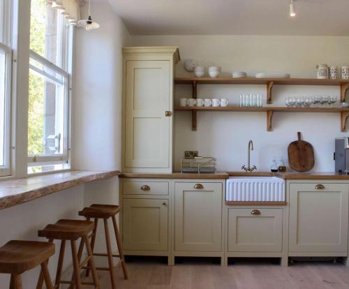 a kitchen with white cabinets and a sink at Dilkusha, Peebles in Peebles